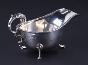 A George III silver sauce boat with scroll handle and shell capped hoofed feet, Chester 1937, 102g.