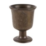 An Islamic bronze mortar engraved with Islamic script, 17cms high.