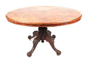 A Victorian walnut loo table with an oval tilt-top on a carved quatreform base, 130cms wide.