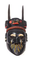 A large South American painted wooden mask with horned headdress and articulated jaw, 99cms high.