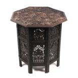 An Anglo-Indian occasional table with profusely carved octagonal top on a conforming collapsible