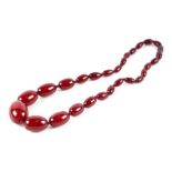 A graduated cherry amber Bakelite bead necklace, the largest bead 27mm long, 33g. Condition Report