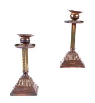 A pair of Arts & Crafts style copper and brass candlesticks with stepped square bases, 17cms high.