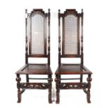 A pair of 16th century style carved oak chairs with cane backs, solid seats and carved front rail (