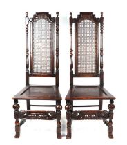 A pair of 16th century style carved oak chairs with cane backs, solid seats and carved front rail (