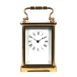 A French brass four-pillar carriage clock, the white enamel dial with Roman numerals, fitted with