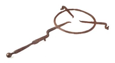 A large 17th / 18th century wrought iron hearth trivet with brass ball handle, 68cms overall