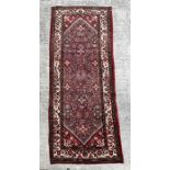 A Persian woollen hand knotted runner with repeat geometric designs within floral borders, on a