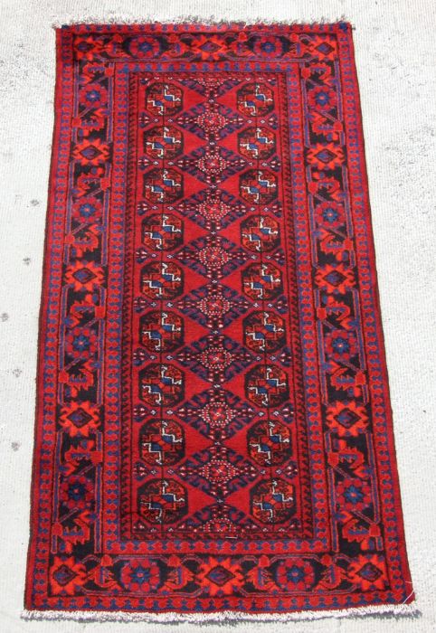 A Persian Turkoman hand knotted runner with repeat geometric design, on a red ground, 230 by