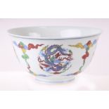 A Chinese Wucai style footed bowl decorated with dragons amongst clouds, six character blue mark