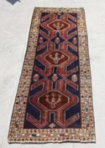 A Persian hand knotted Afshar runner with central stylised design, on a navy ground, 290 by 110cms.