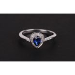 A 9ct white gold diamond and sapphire ring, the pear shaped central sapphire (possibly Ceylon)