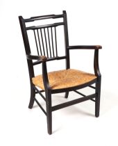 An ebonised elbow chair with rush seat.