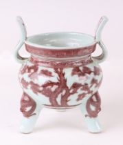 A Chinese two-handled three-legged red and white censer, 20cms high.