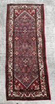 A Persian woollen hand knotted runner with repeat geometric designs within floral borders, on a