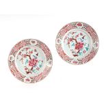 A pair of Chinese famille rose plates decorated with flowers, on a pink ground, 23cms diameter (