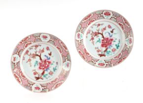 A pair of Chinese famille rose plates decorated with flowers, on a pink ground, 23cms diameter (