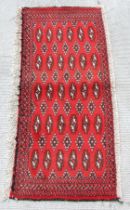 A Persian Turkoman woollen hand-made small rug with geometric designs on a red ground, 130 by