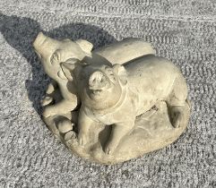 A reconstituted stone recumbent pig and piglets, 50cms wide; together with another similar garden