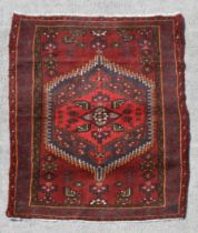 A Persian Hamadan hand knotted woollen rug with stylised design within borders, on a red ground, 140