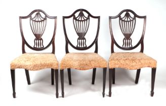 Three Hepplewhite style mahogany dining chairs with shield shaped backs and urn shaped pierced