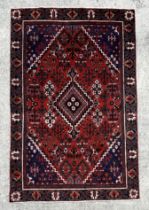 A Persian Shiraz hand knotted woollen rug with central diamond gul within a floral border, on a