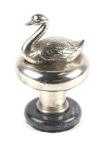 An accessory car mascot in the form of a swan, mounted on a plinth.