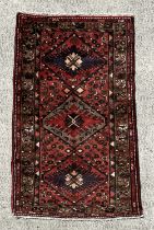 A Persian Hamadan wool carpet with three central guls within geometric borders, on a red ground, 146