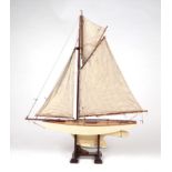 An Edwardian painted pond yacht with fully rigged sails and lead keel, mounted on a stand, 102cms