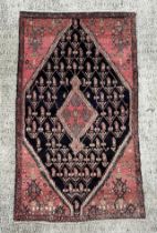 A Persian hand knotted Hamadan rug with large central diamond gul, on a red ground, 160 by 100cms (