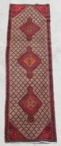 A Persian hand knotted runner with repeat design within a geometric border, on a beige ground, 290