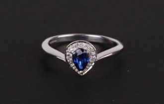 A 9ct white gold diamond and sapphire ring, the pear shaped central sapphire (possibly Ceylon)