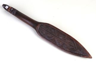 A Maori carved wooden dance paddle with Tiki inlay decoration, 48cms long.