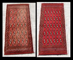 Two small Persian Turkoman woollen hand-made rugs with geometric designs on a red ground, each