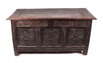 An 18th century oak coffer with carved frieze above three carved panels, both sides with carved
