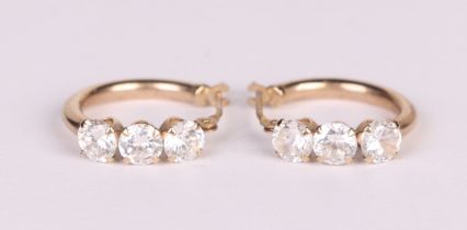 A pair of 9ct gold hoop earrings, each set with three white stones.