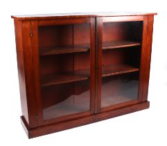 A Victorian mahogany glazed bookcase, the pair of doors enclosing a shelved interior, on a plinth