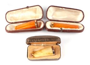 A late Victorian or Edwardian amber cheroot holder with 9ct gold collar, cased; together with two