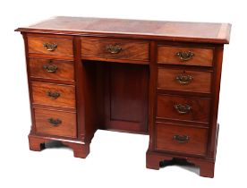 An Edwardian walnut kneehole desk with inset leather top above an arrangement of nine drawers and