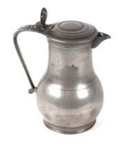 An 18th / 19th century pewter lidded jug with shell shaped thumb piece, 24cms high.