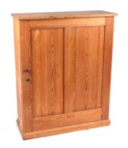 A pine side cabinet with single twin panelled door enclosing a shelved interior, on a plinth base,