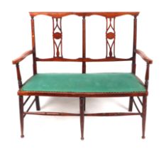 An Edwardian double chair-back two-seater sofa, on ring turned legs, 106cms wide.