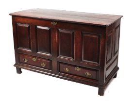 An 18th century oak mule chest, the hinged top above four panels and two drawers, on stile feet,