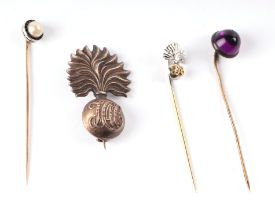 A 9ct gold Royal Fusiliers stick pin; together with a similar cap badge; and two other stick pins (