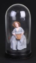 A Folk Art carved wooden doll in a gingham dress, under a glass dome, 20cms high.