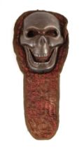 A Tibetan cast metal half skull on a textile, 34cms high.