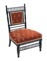 In the manner of Godwin, an ebonised nursing chair with upholstered seat and back.
