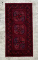 A Persian rug with central guls within a multi border, on a red ground, 140 by 70cms.