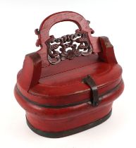 A Chinese red lacquer food box with pierced swing handle decorated with a phoenix, 31cms wide.