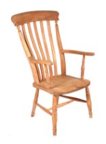 A pine kitchen armchair with slat back, solid seat and turned front legs joined by a stretcher.